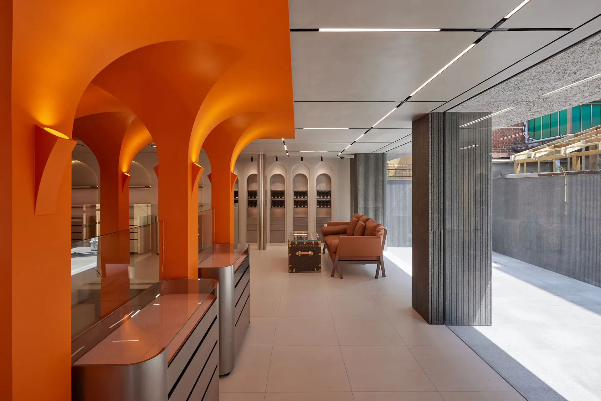A modern restaurant interior with orange walls and concrete columns.
