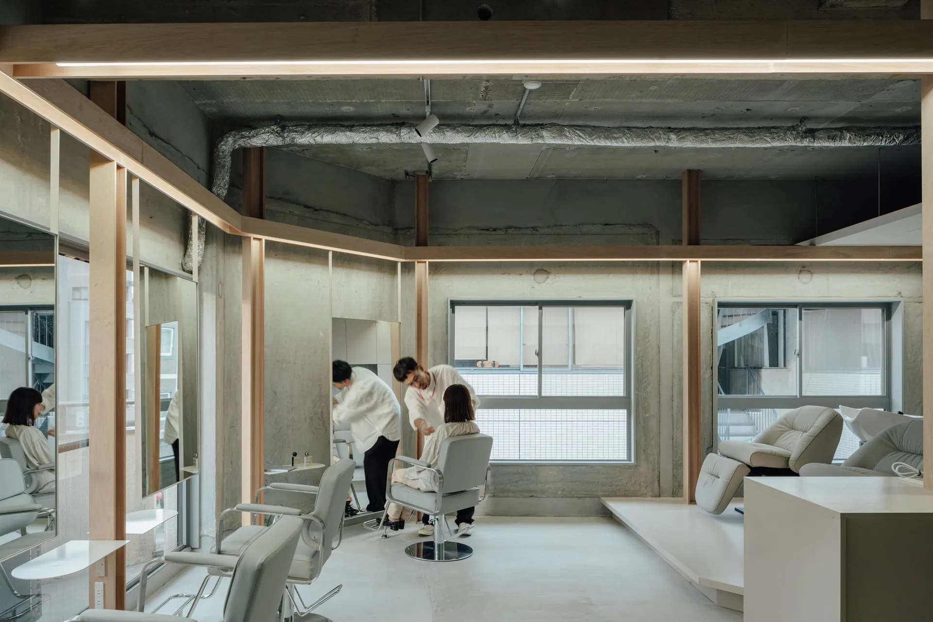 A modern salon featuring minimalist design with concrete walls and white furniture.