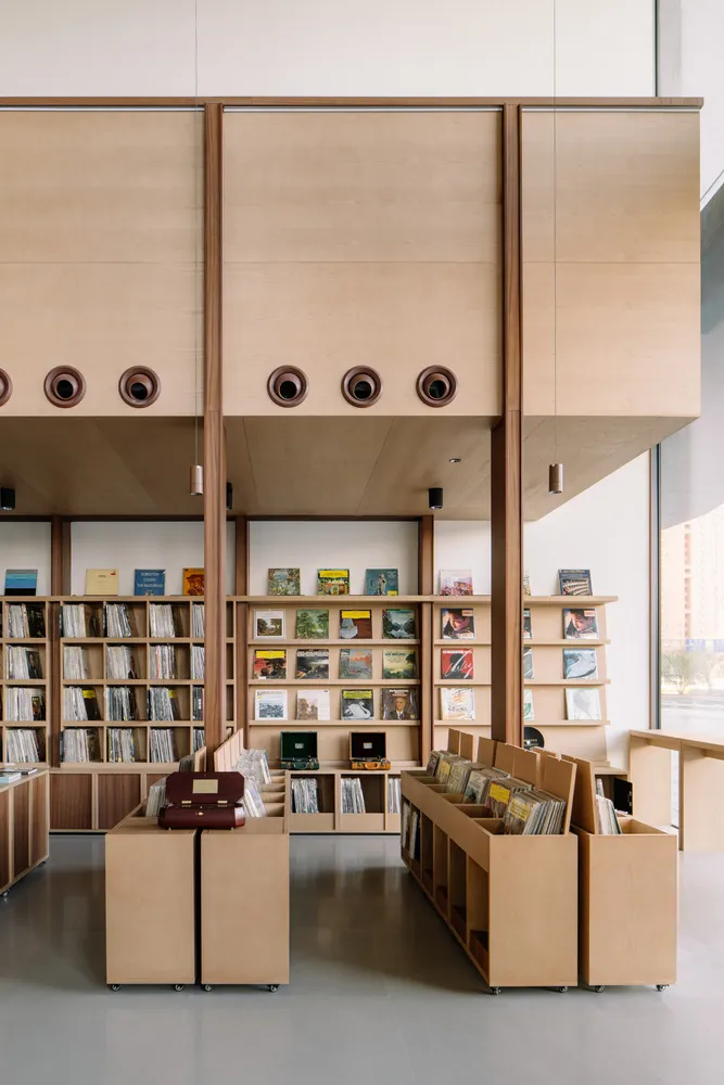 Industrial-style library with wooden bookshelves and furniture, featuring a variety of books.