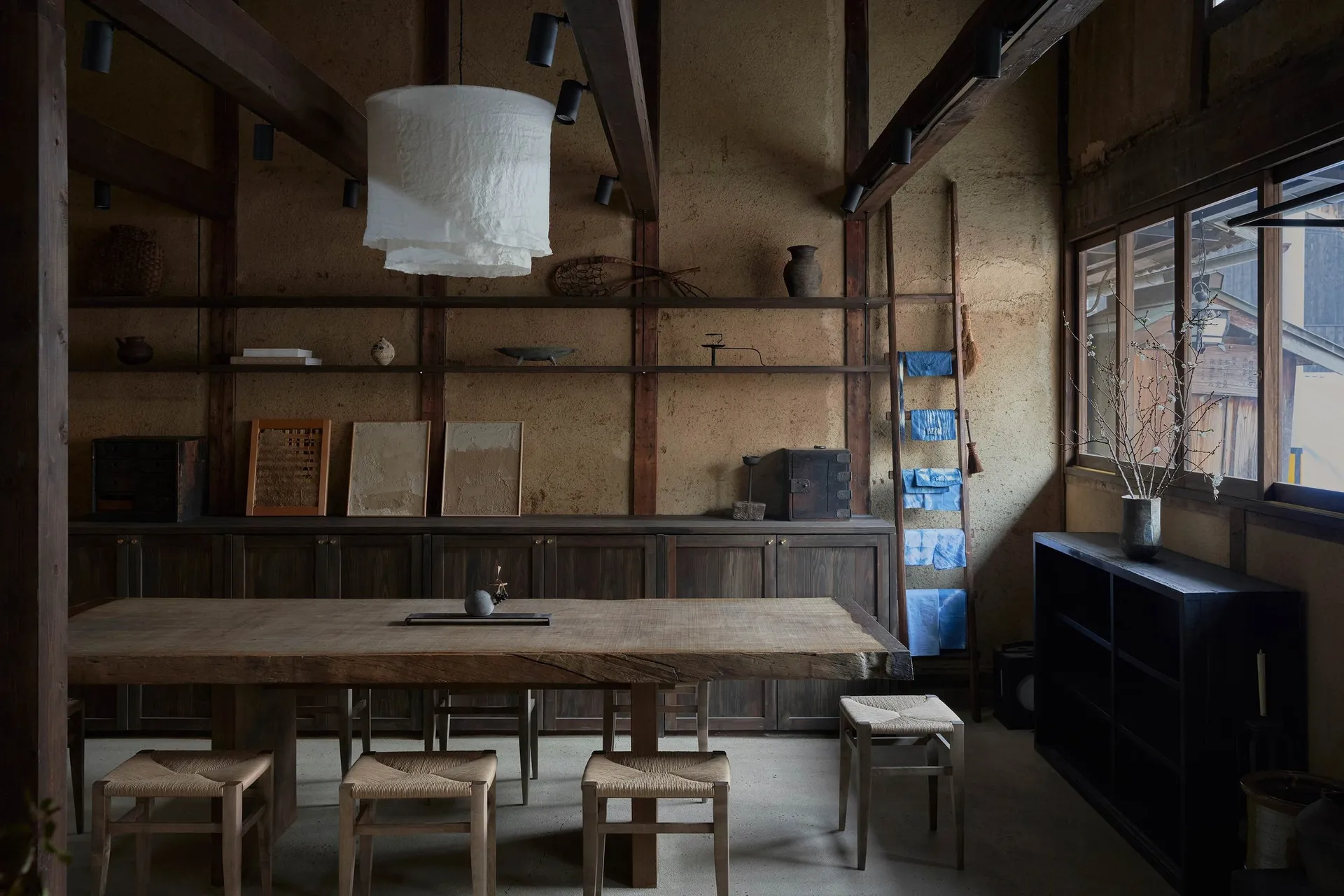 A minimalist Japanese dining room featuring a wooden table and chairs in a rustic setting.