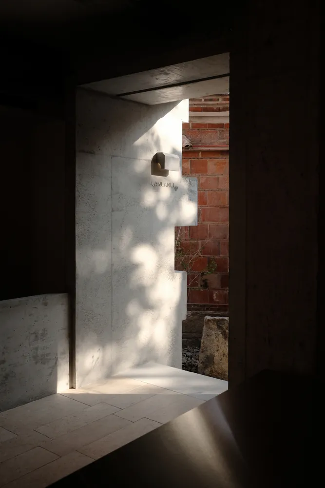 A modern interior space featuring exposed concrete walls and recessed lighting, creating a minimalist and industrial aestheti