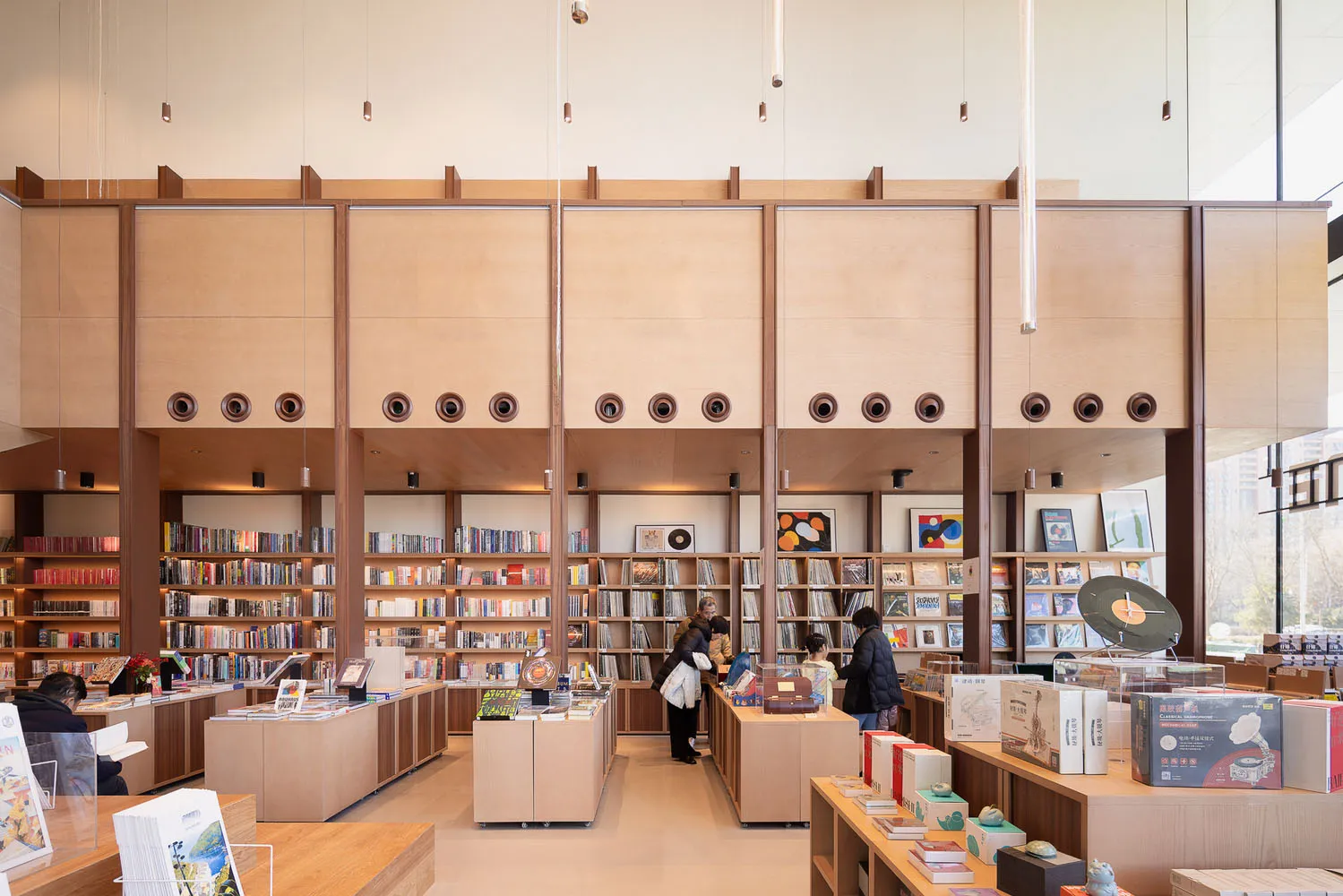 A modern library interior with wooden shelves and glass display cases.