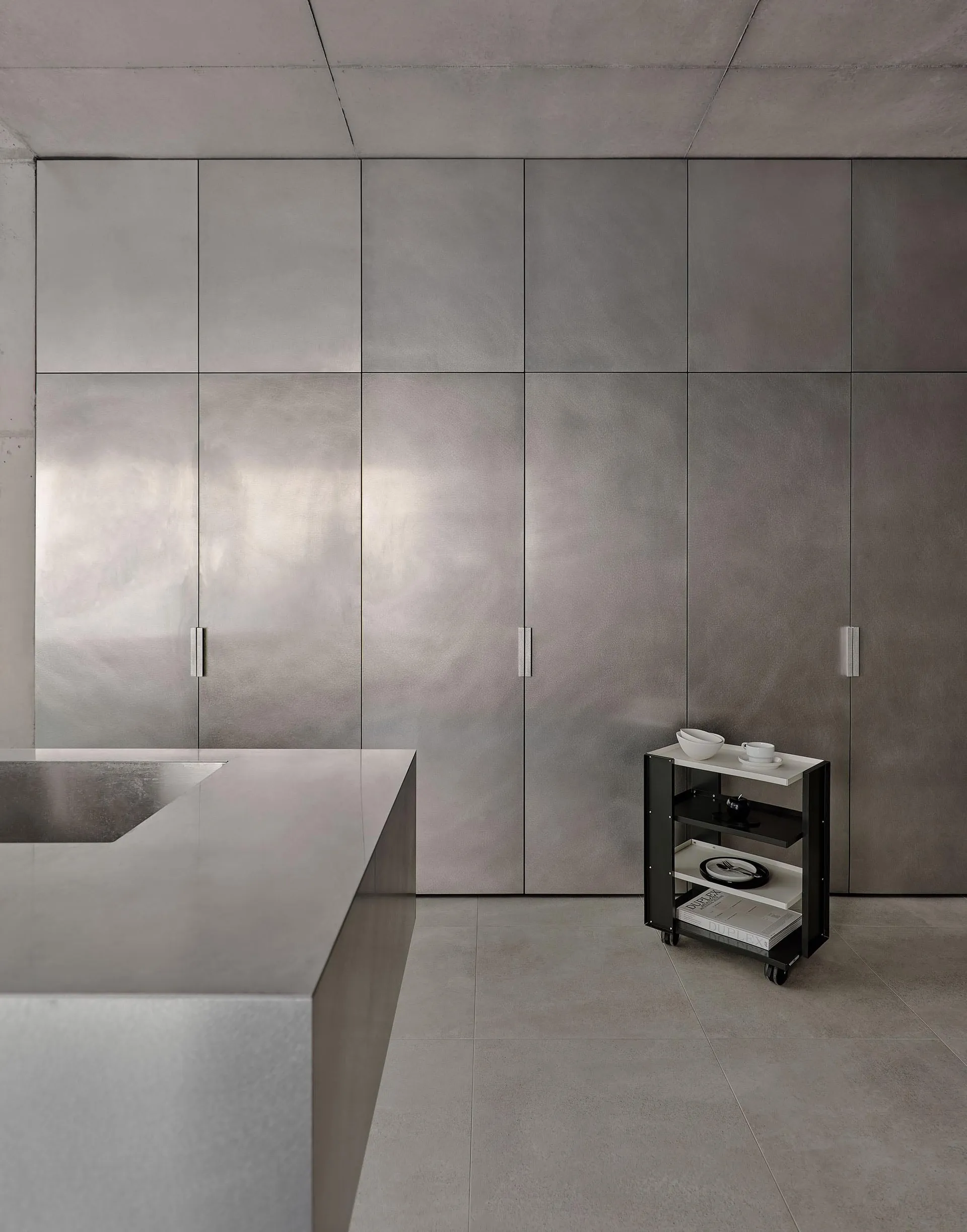 A streamlined, modern kitchen with metallic cabinetry and a large countertop.
