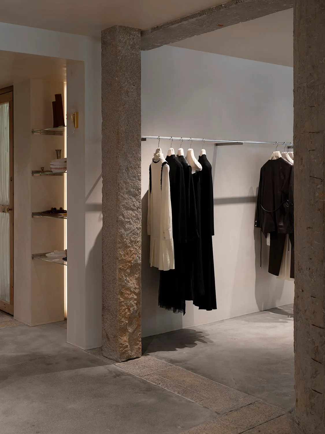 A modern retail store with concrete floors displaying clothing on a hanging rail.