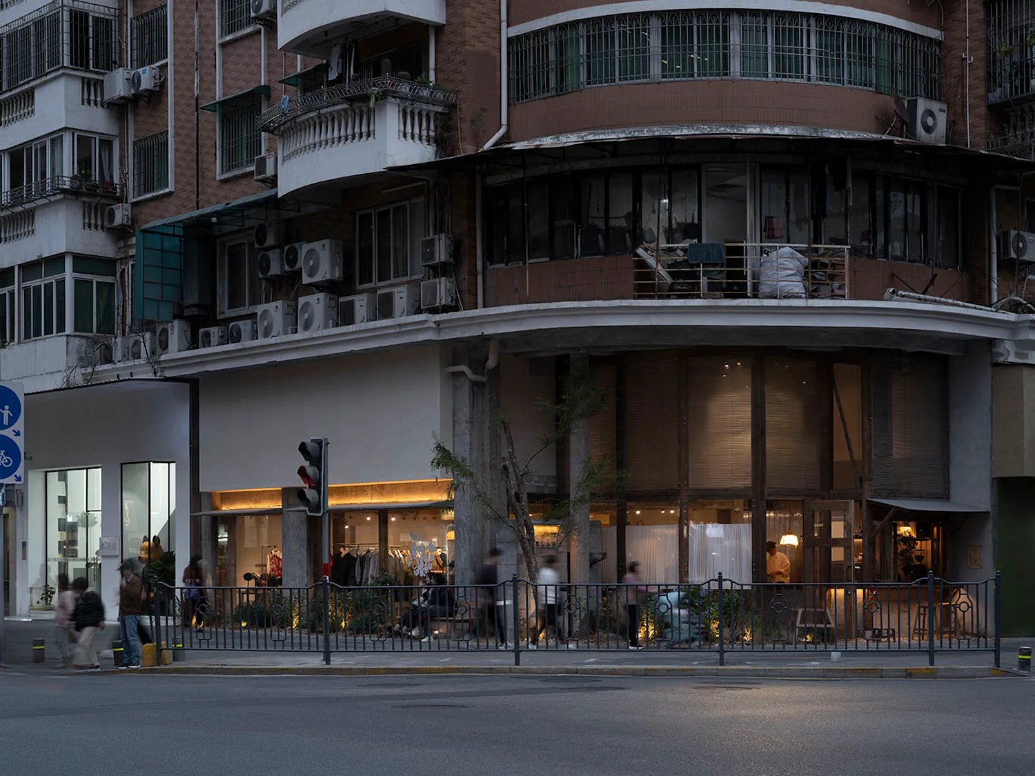 An exterior view of a modern retail storefront featuring concrete, glass, and metal materials.