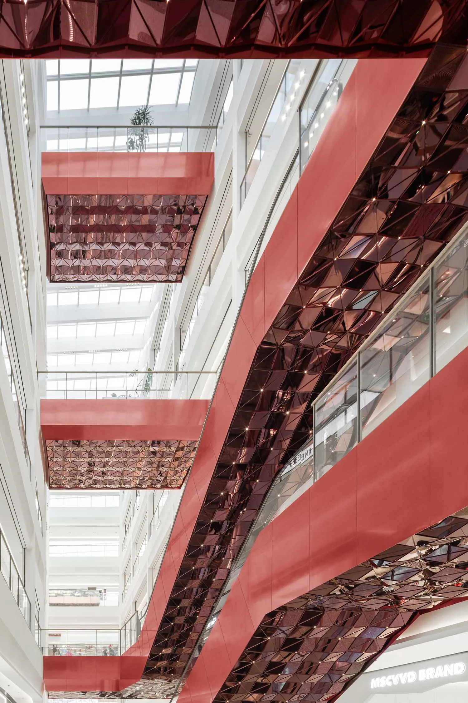 Modern shopping center interior with metallic reflective ceiling panels.