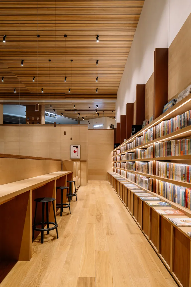 Interior view of a modern library with wooden shelves and stools