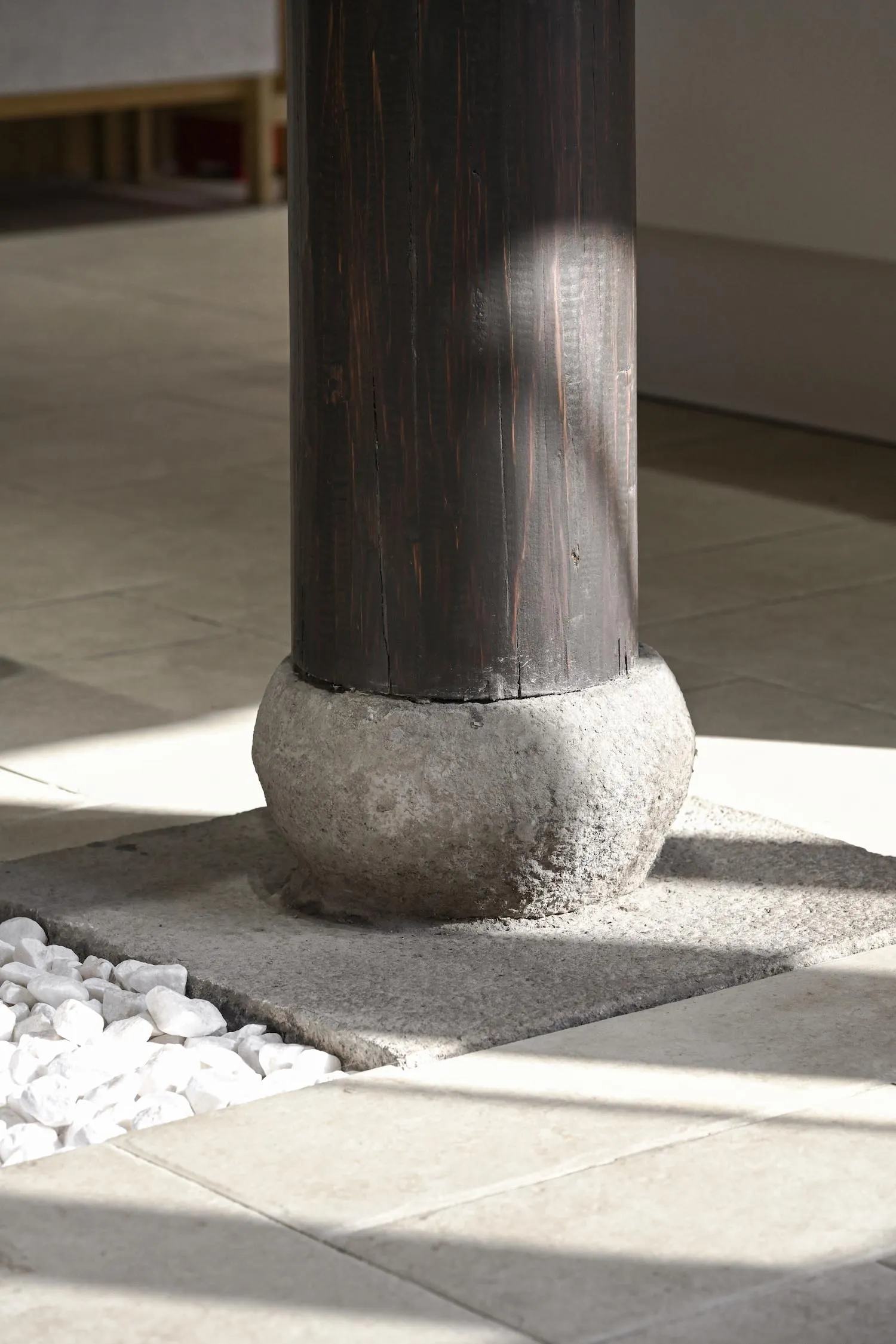 A dark wooden pillar base in a modern interior lobby setting.