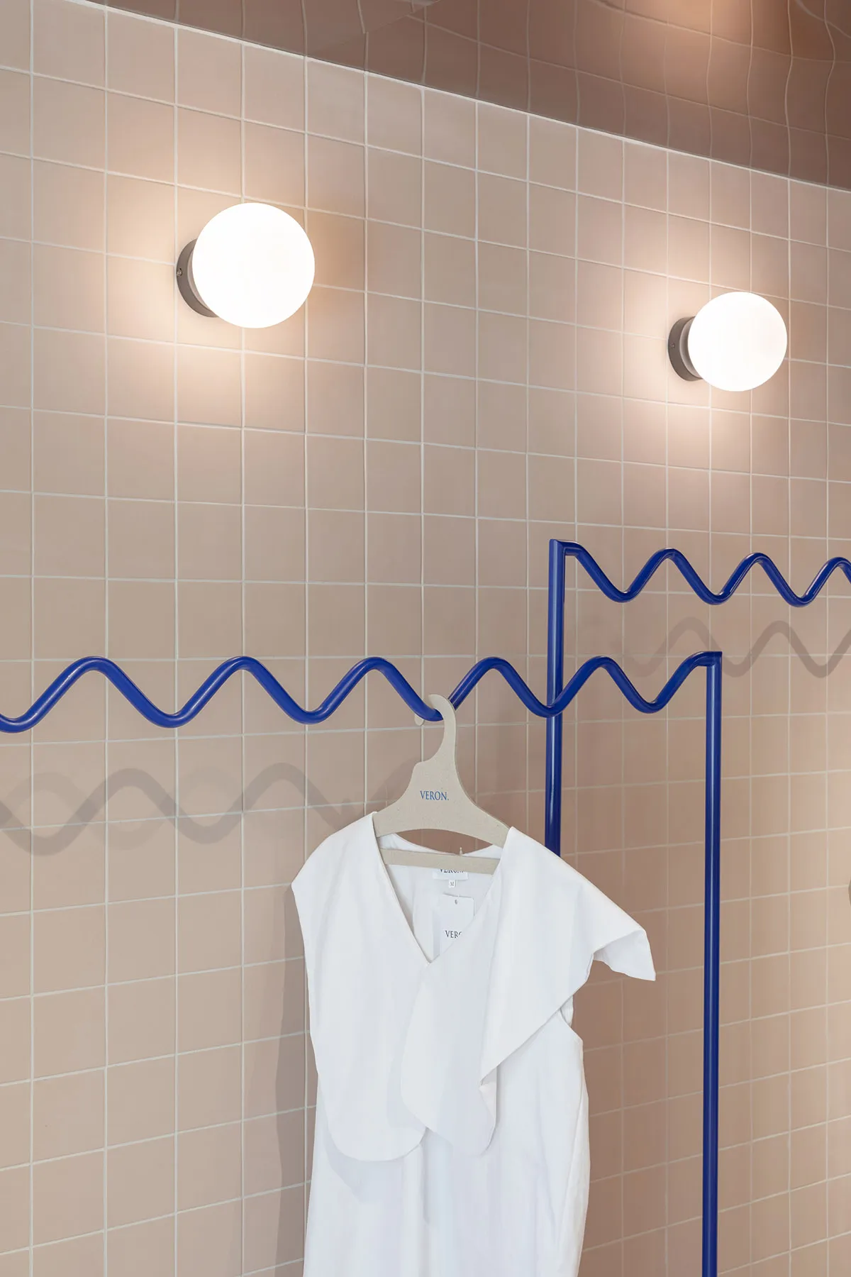 Modern industrial clothing display featuring a minimalist design with a white garment hanging on a metal hanger.