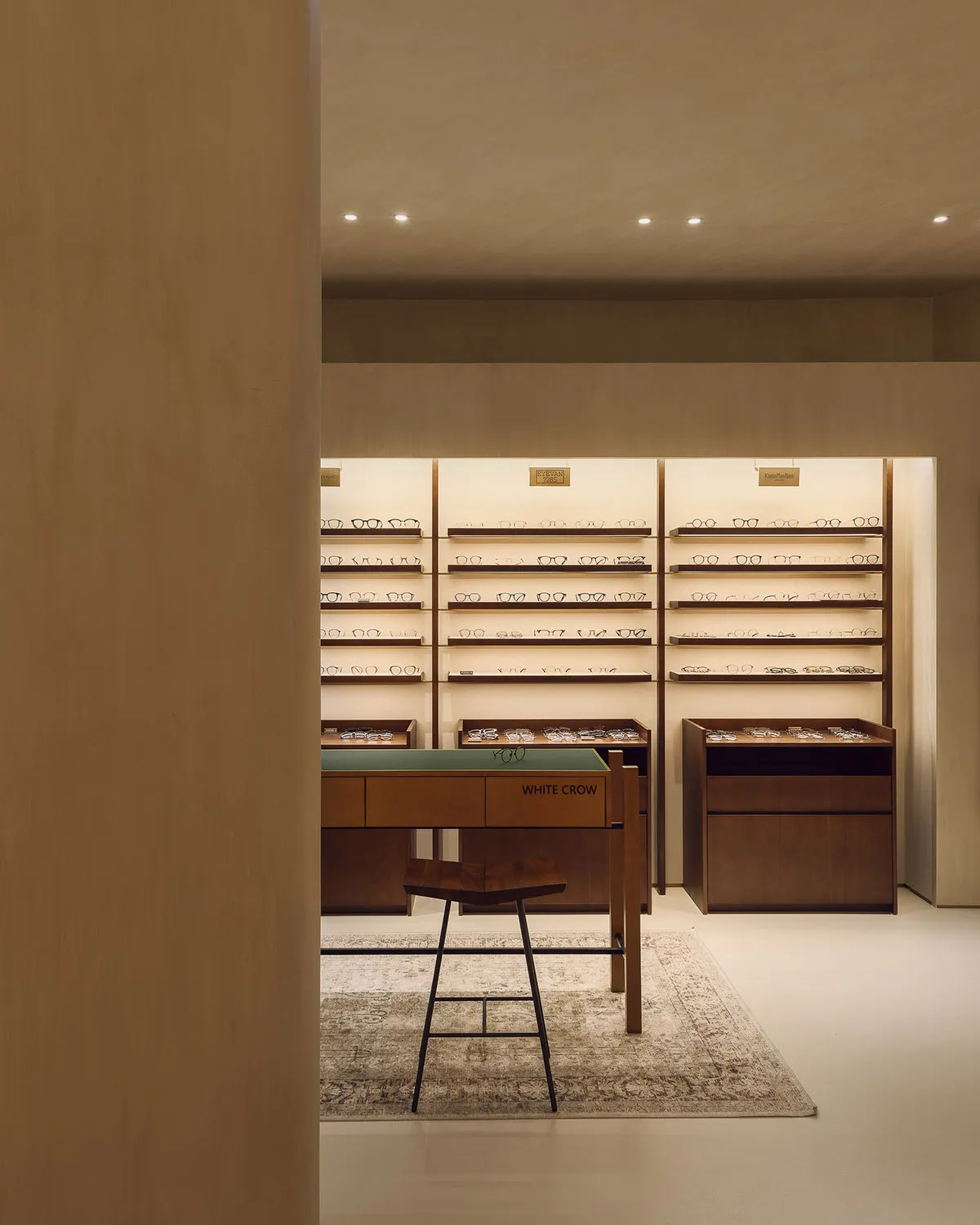 Modern minimalist optical store featuring wooden shelves and display furniture with an array of eyeglasses.