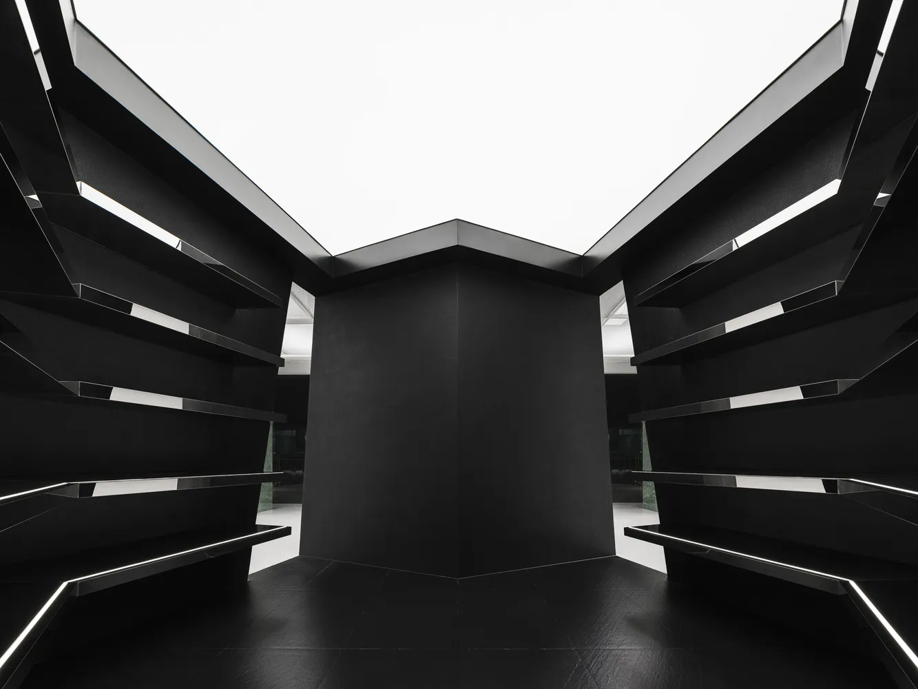An empty black and white indoor room with geometric shapes and a tall, central structure.