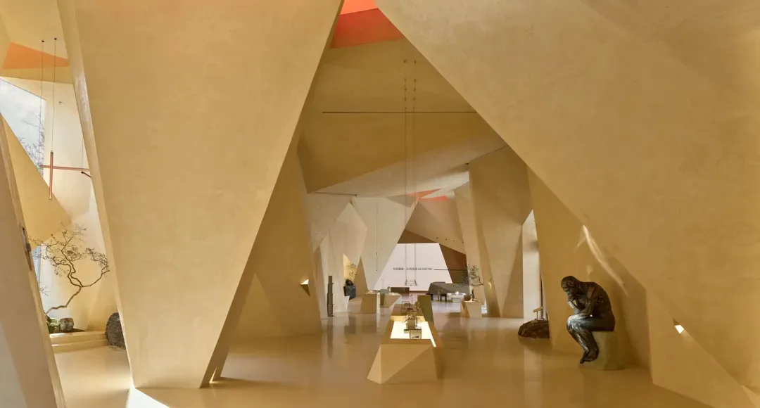 Modern art gallery space with angular architectural features and sandstone concrete walls