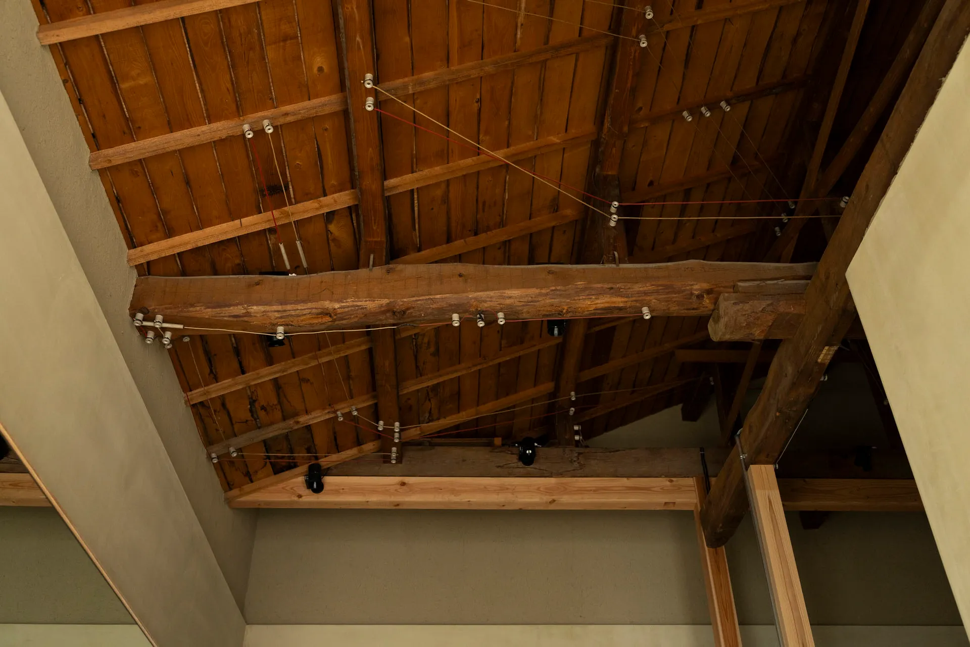 Editorial photograph of a wooden ceiling with exposed beams and wiring