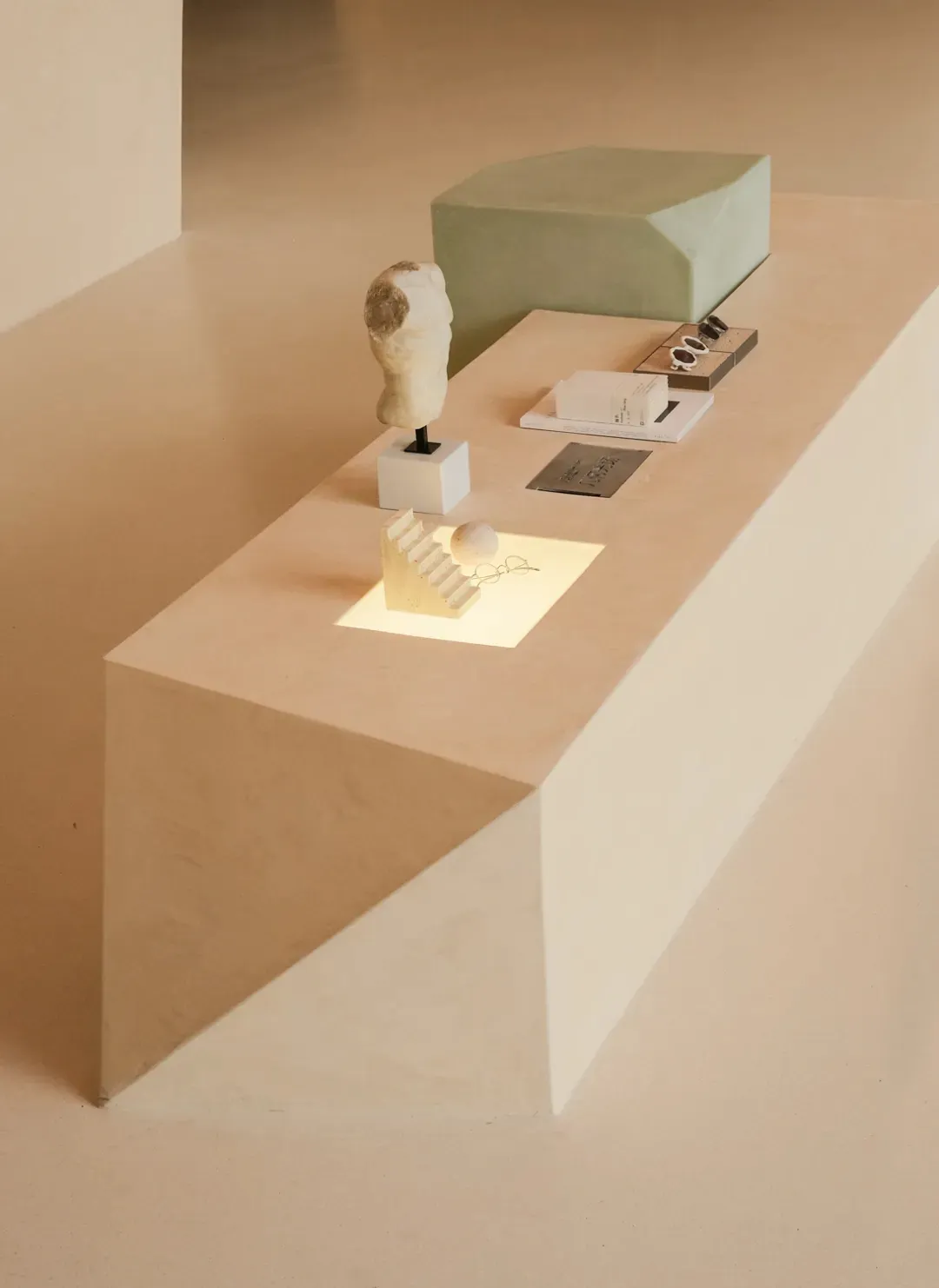 A minimalist product display featuring a sculpture, a cube, and various business cards on a light-colored, geometric platform