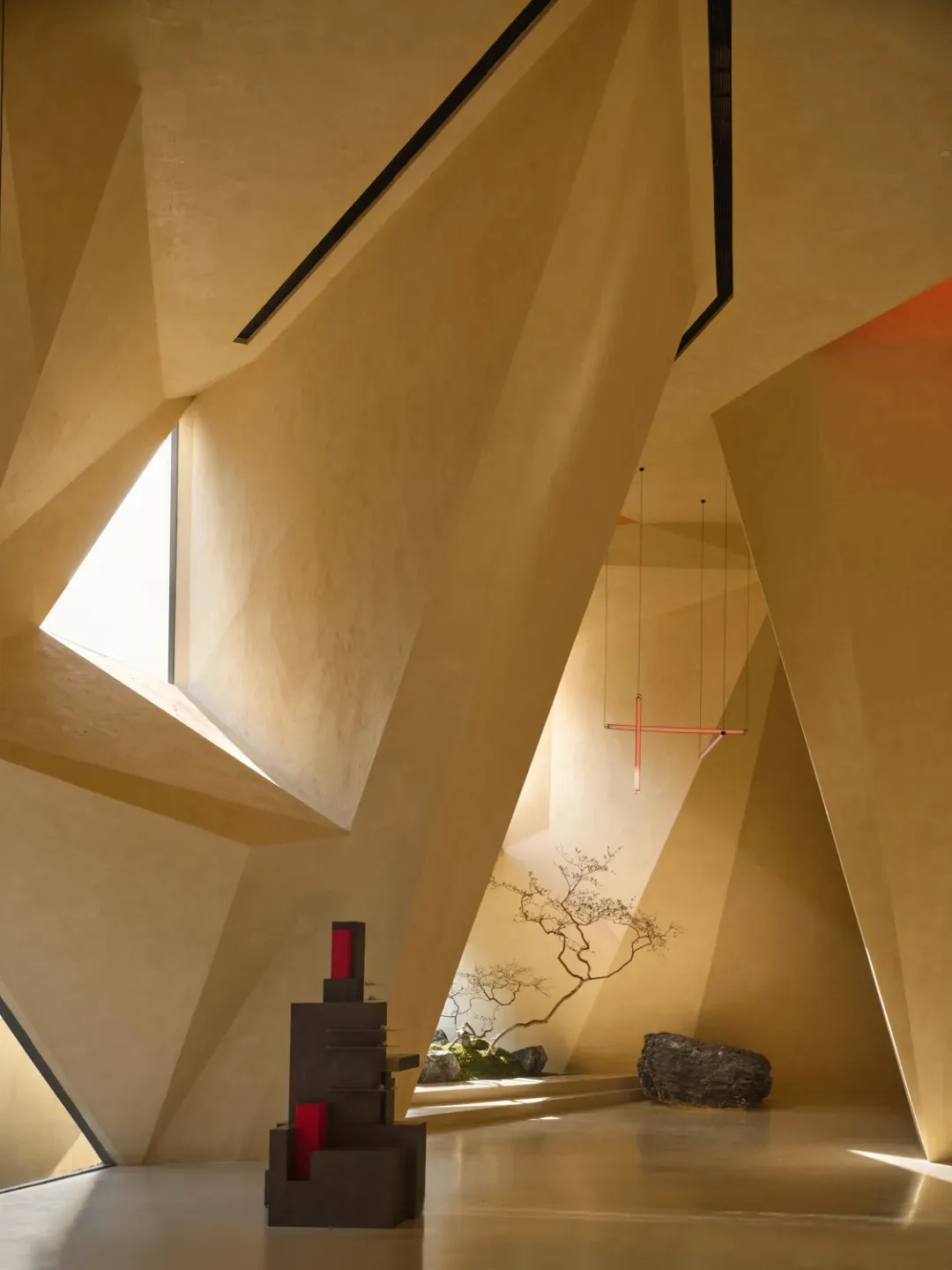 A modern interior space with concrete walls, a hanging light fixture, and geometric architectural features.