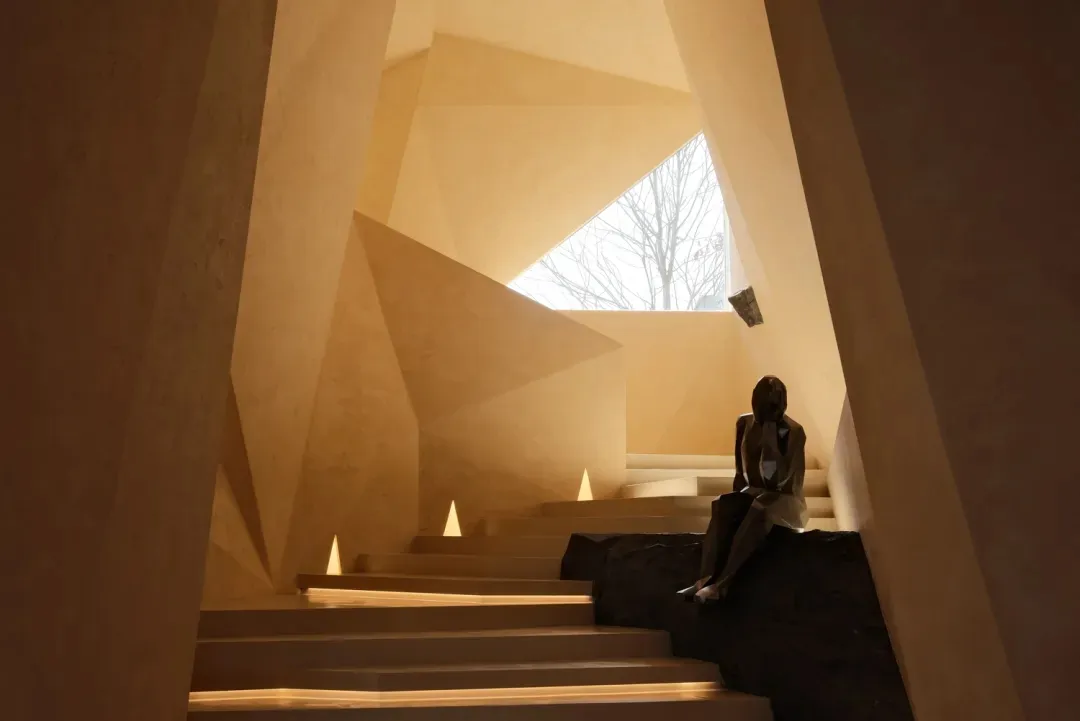 A minimalist concrete staircase with geometric shapes and a skylight in the background.