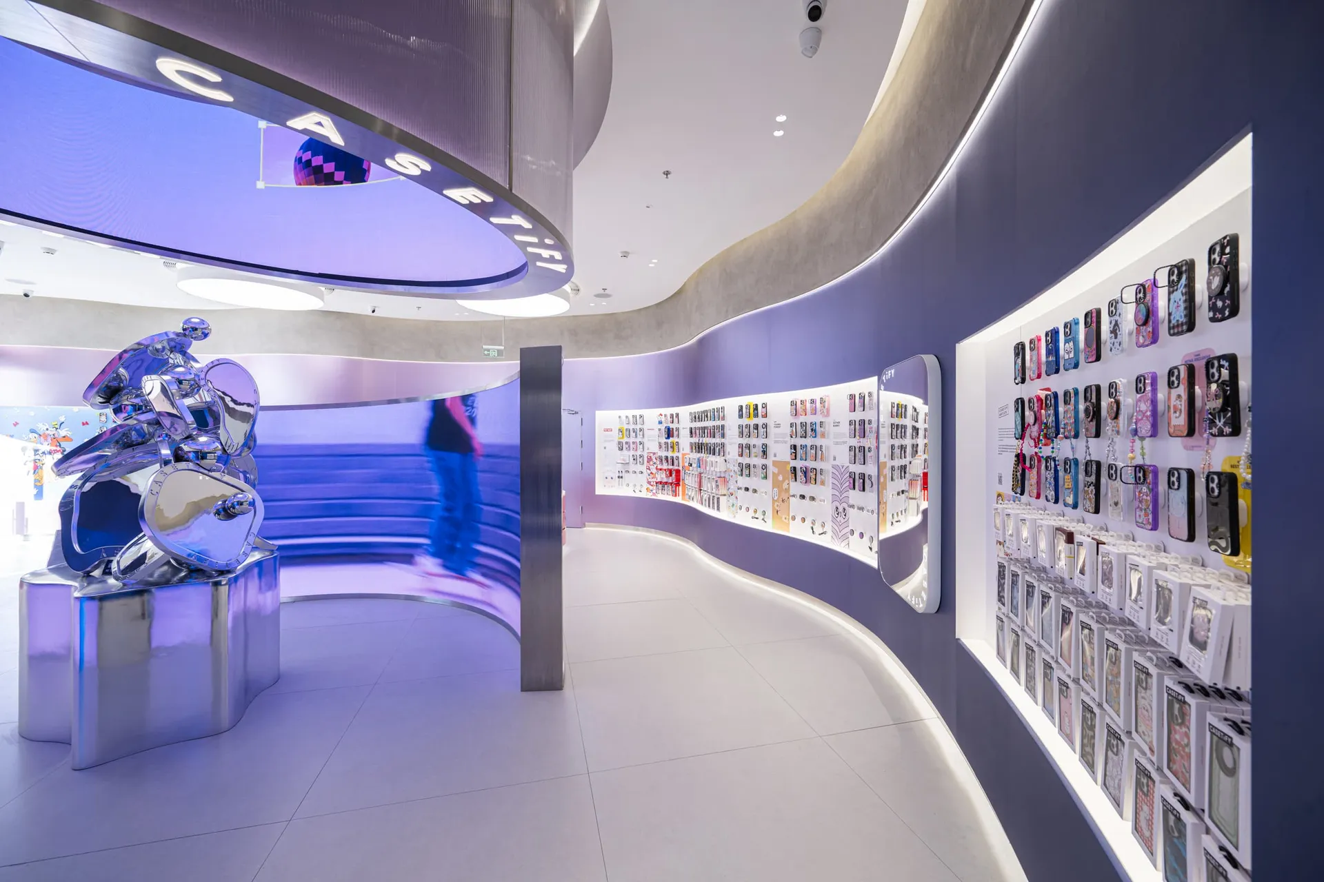 A modern retail store featuring a digital screen and metallic elements, surrounded by various mobile accessories.