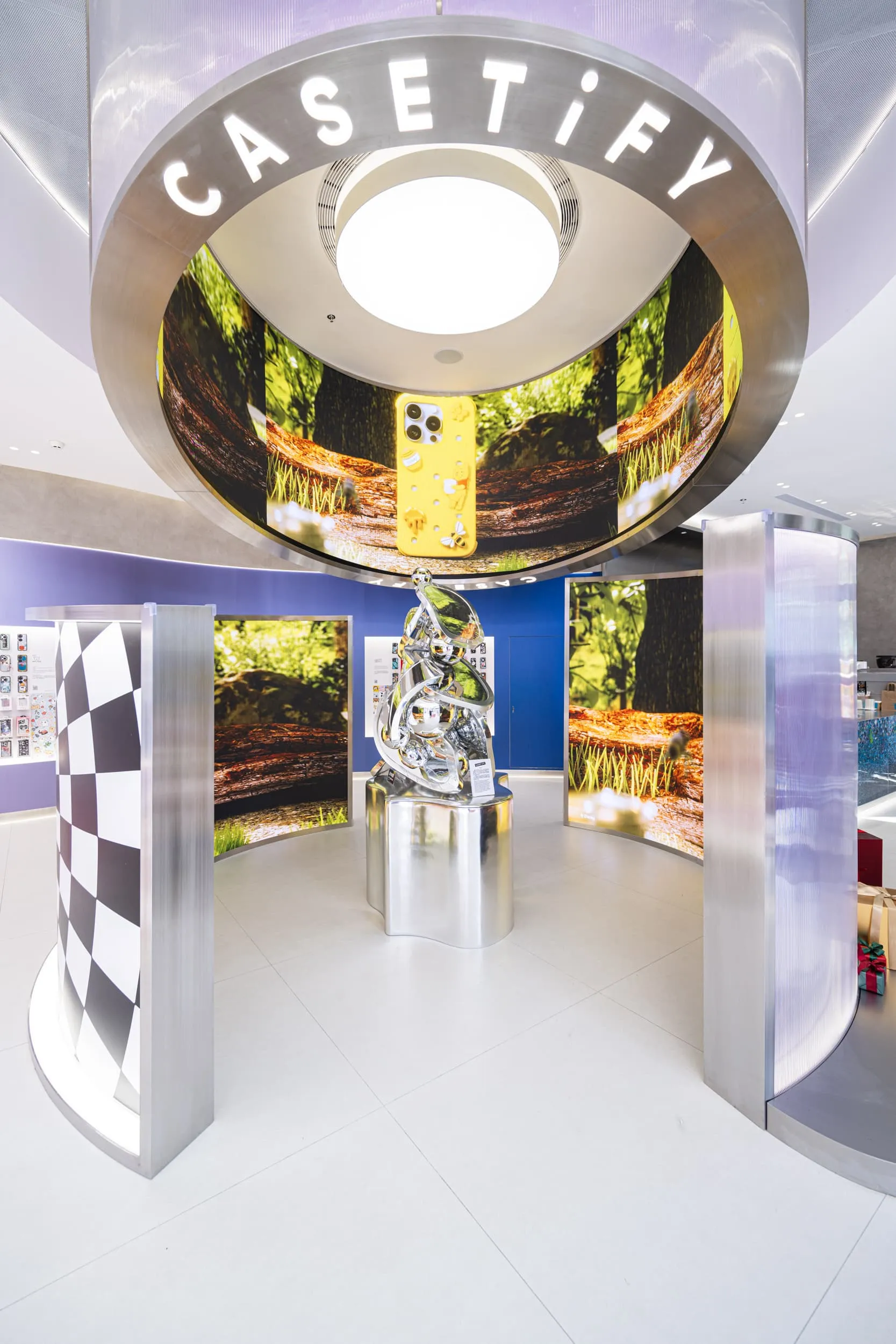 An immersive Casetify display featuring metallic sculptures and digital displays showcasing products and nature-inspired them