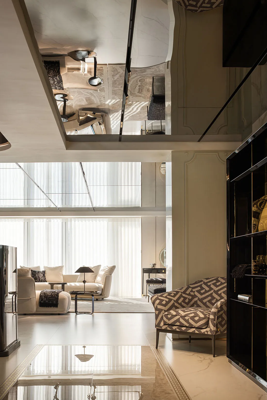 Modern living room featuring sleek, glass furniture with geometric patterns, large windows, and contemporary decor.