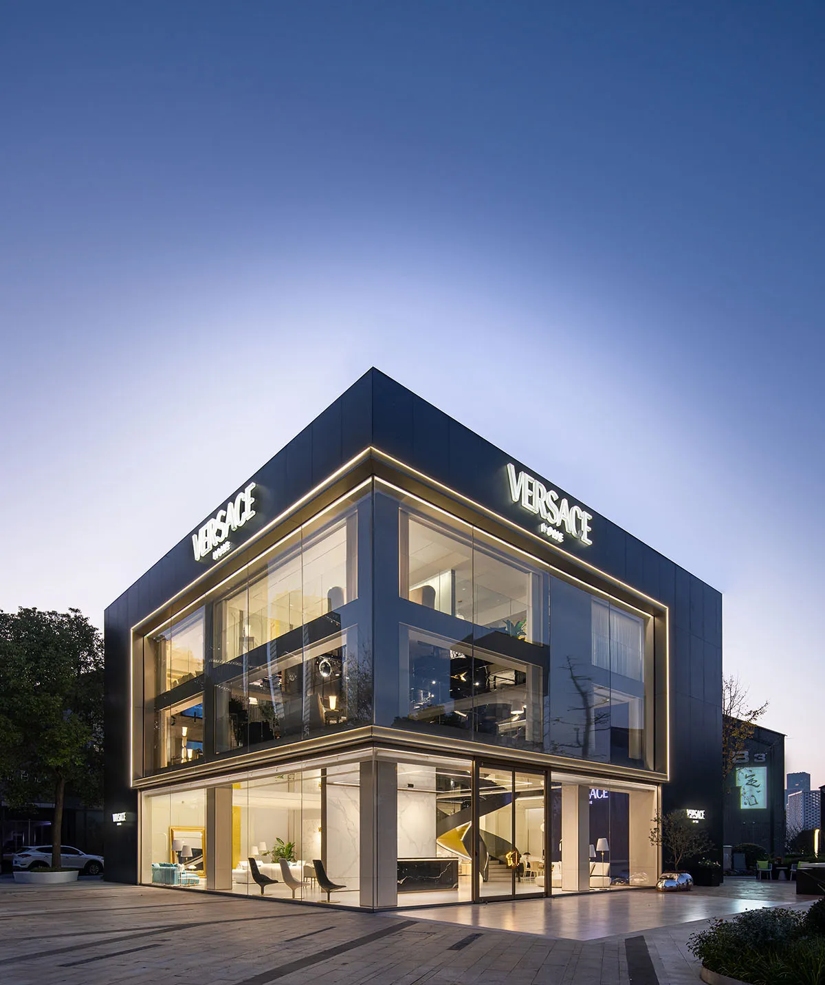 Modern Versace storefront with black metal accents and glass facade at dusk