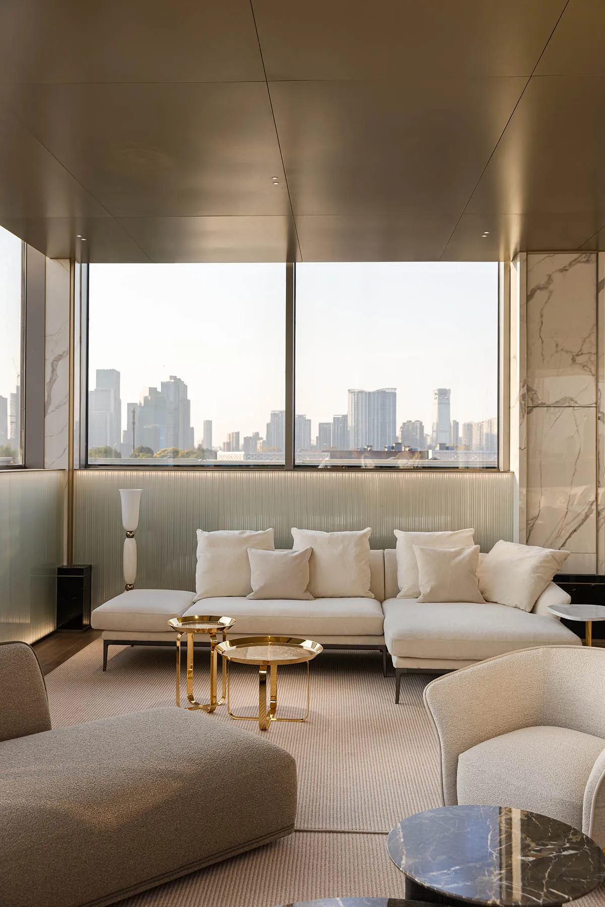 A contemporary living room featuring neutral-toned interiors, plush seating, and a panoramic city view.