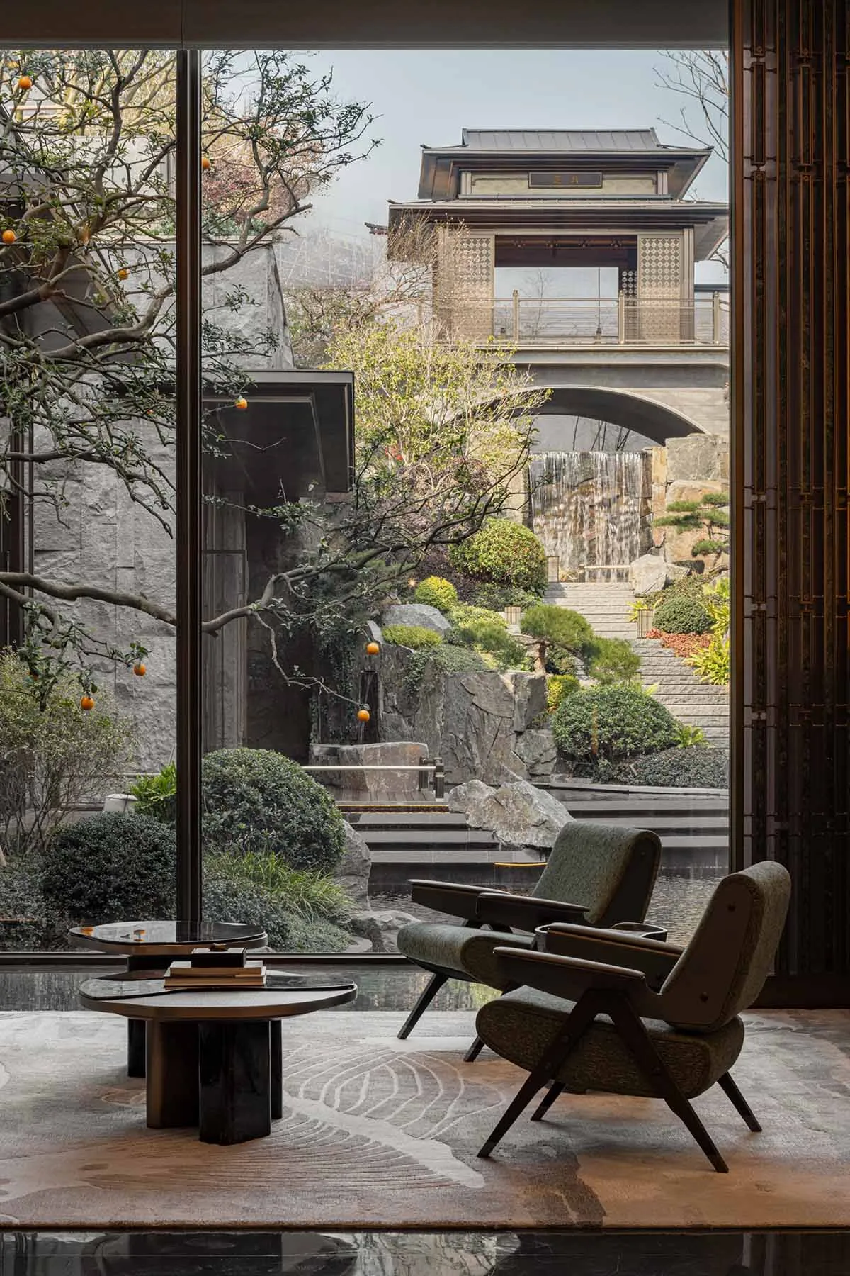 An elegant and modern residential interior featuring warm wood, stone, and glass finishes.