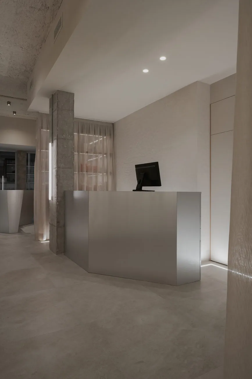 A sleek, modern office reception space featuring a concrete floor and minimalist design.