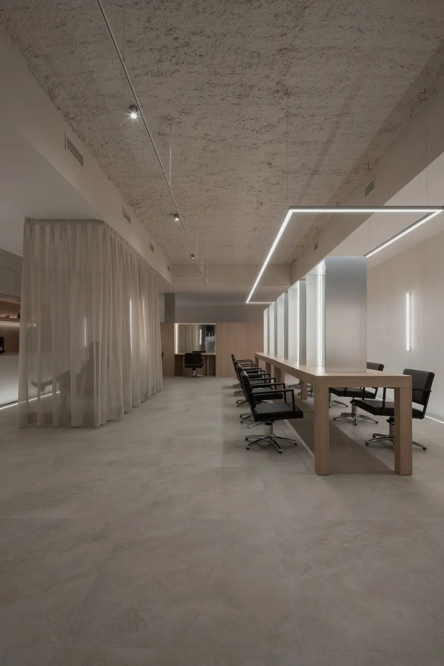 A minimalist modern office space featuring a concrete wall and white curtains.