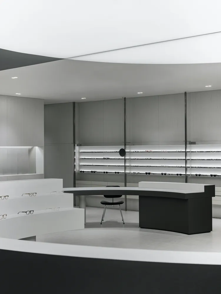 A modern retail storefront with minimalist design featuring black and white color palette, concrete and glass materials, and