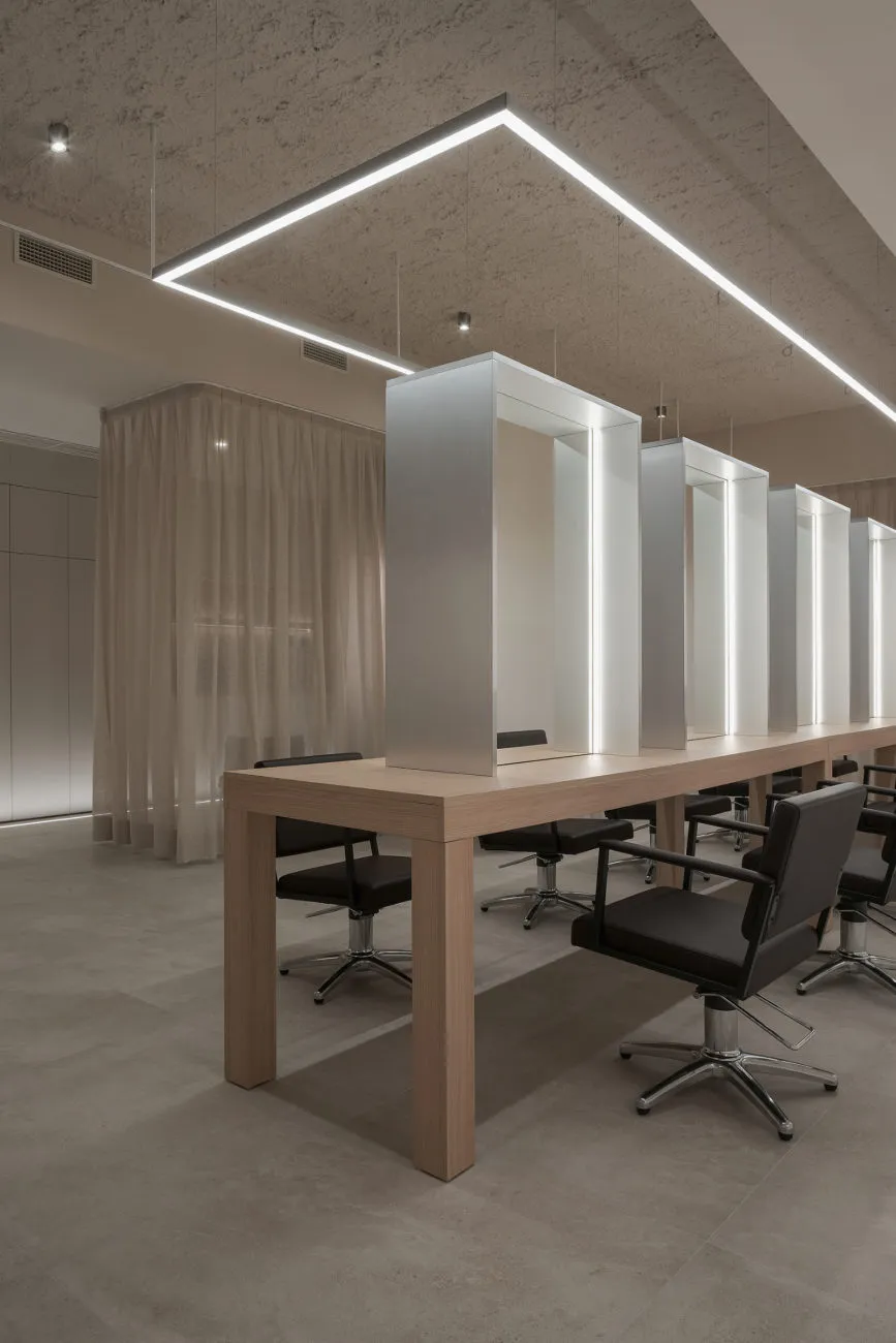 A modern salon interior with a wooden table and black chairs.
