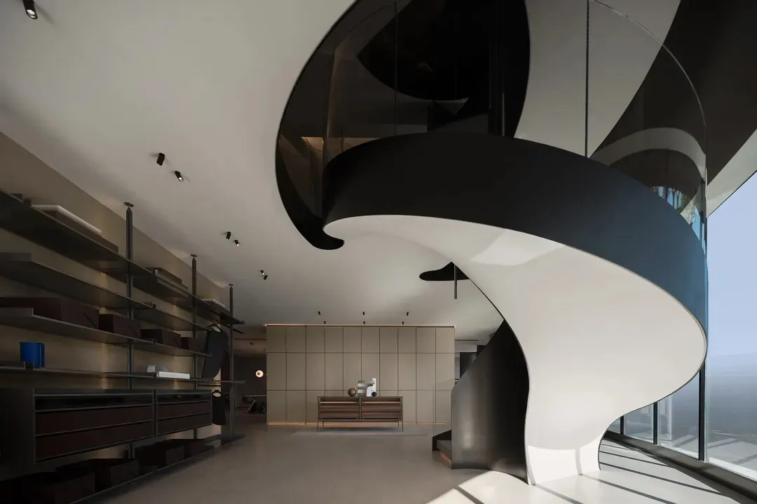 A modern lobby with glass spiral staircase, black and white color scheme, and minimalist design elements.