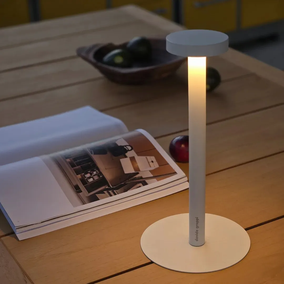 A sleek, modern table lamp made of aluminum on a wooden table.