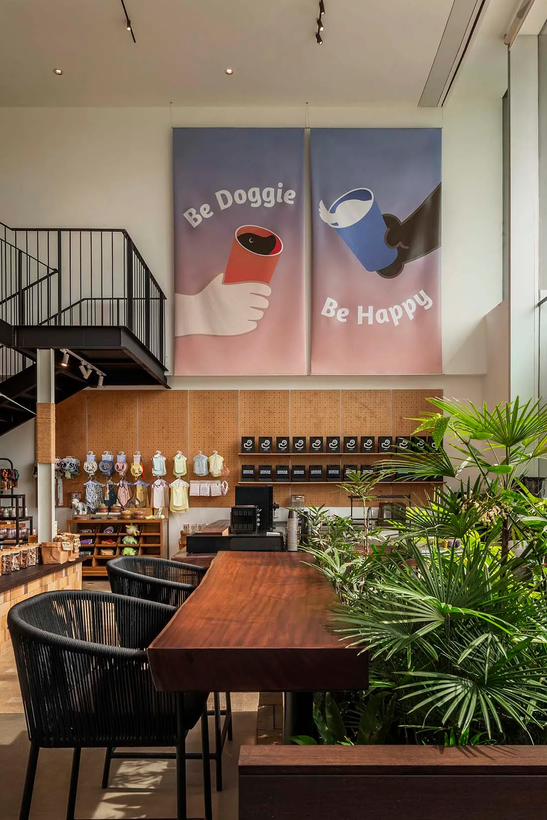 Modern coffee shop interior with wooden tables, metal chairs, and glass display cases.