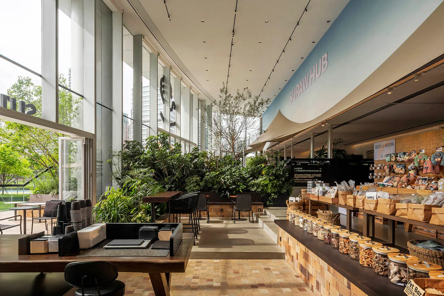 A spacious pet shop interior with modern design, featuring large windows, wooden shelves, and a lush plant-filled interior sp
