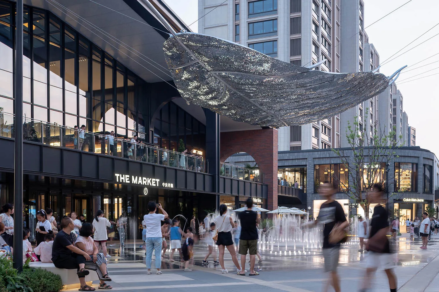 A bustling urban space featuring architectural elements made from metal, glass, and concrete.