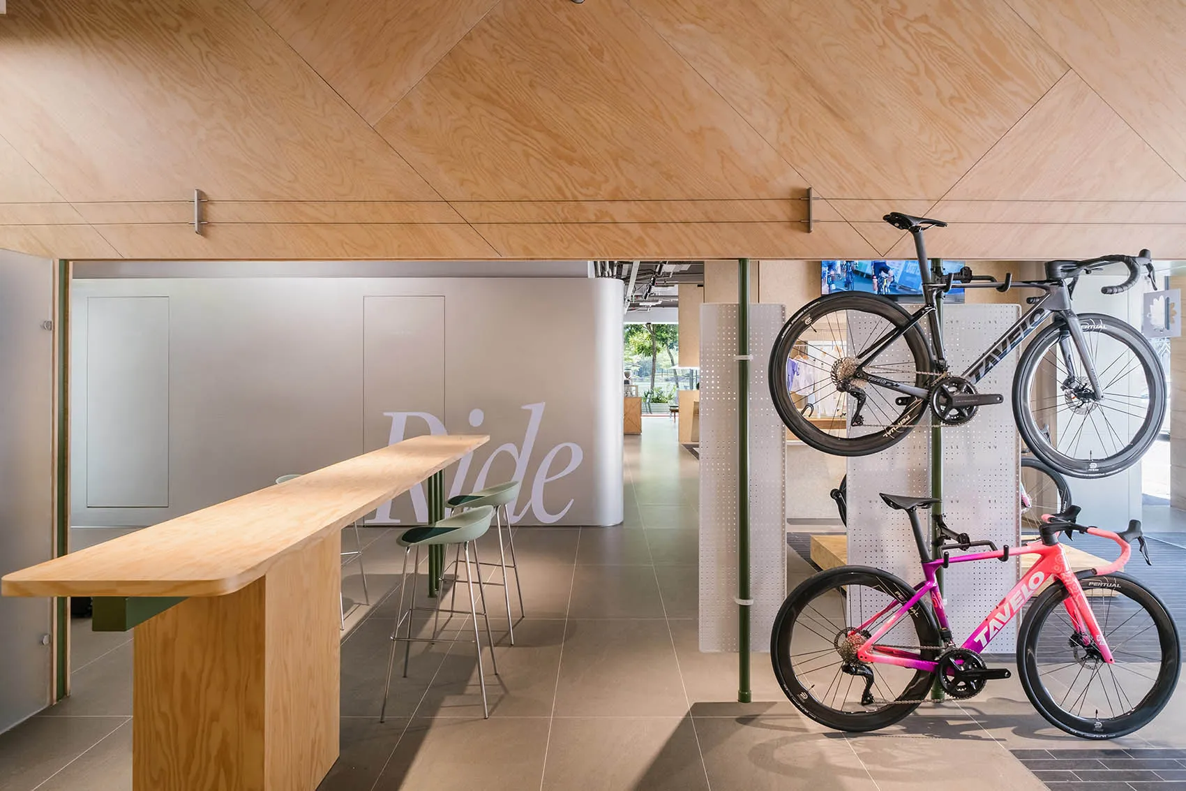 A bike shop interior with wooden walls and hanging bicycles on display.