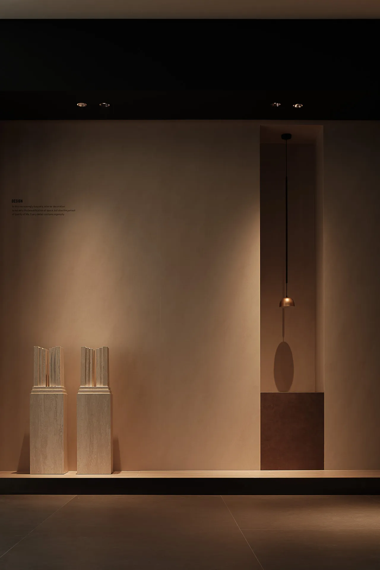 Minimalist display featuring stone columns and a metallic hanging light.
