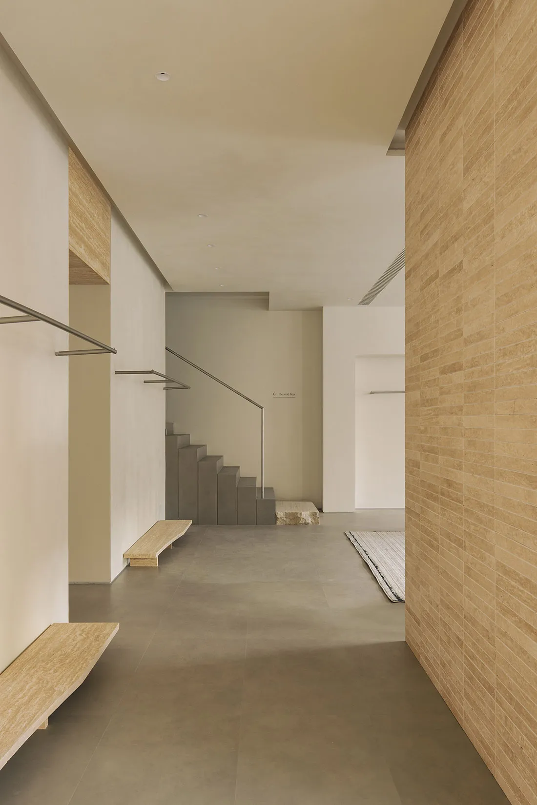 A modern entryway with a concrete floor and steps leading up to a glass door.