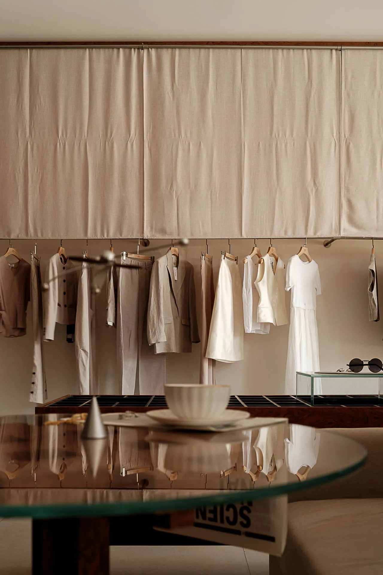 A clothing shop display featuring wood hangers with boho-inspired outfits hanging on a curtain-covered wall.
