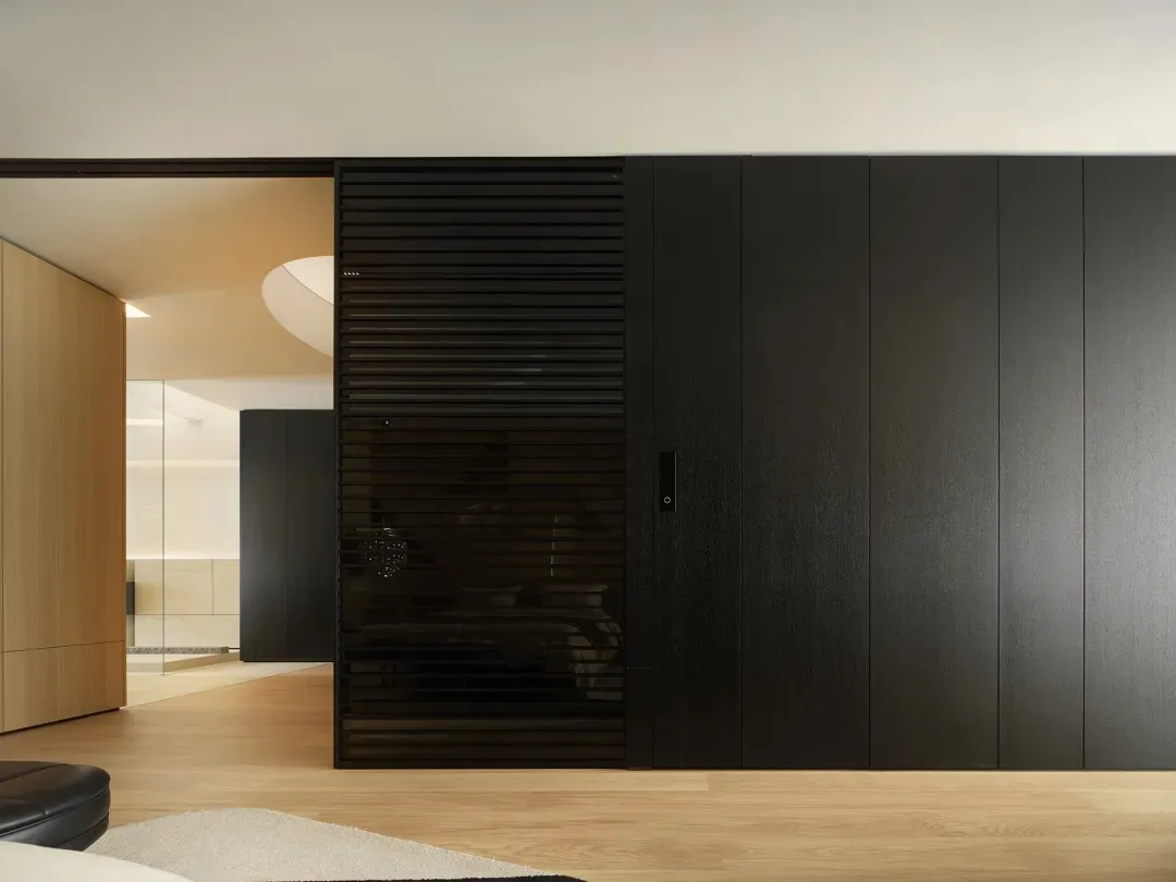 Modern interior design featuring black and wooden furnishings, glass panels, and minimalist decor.