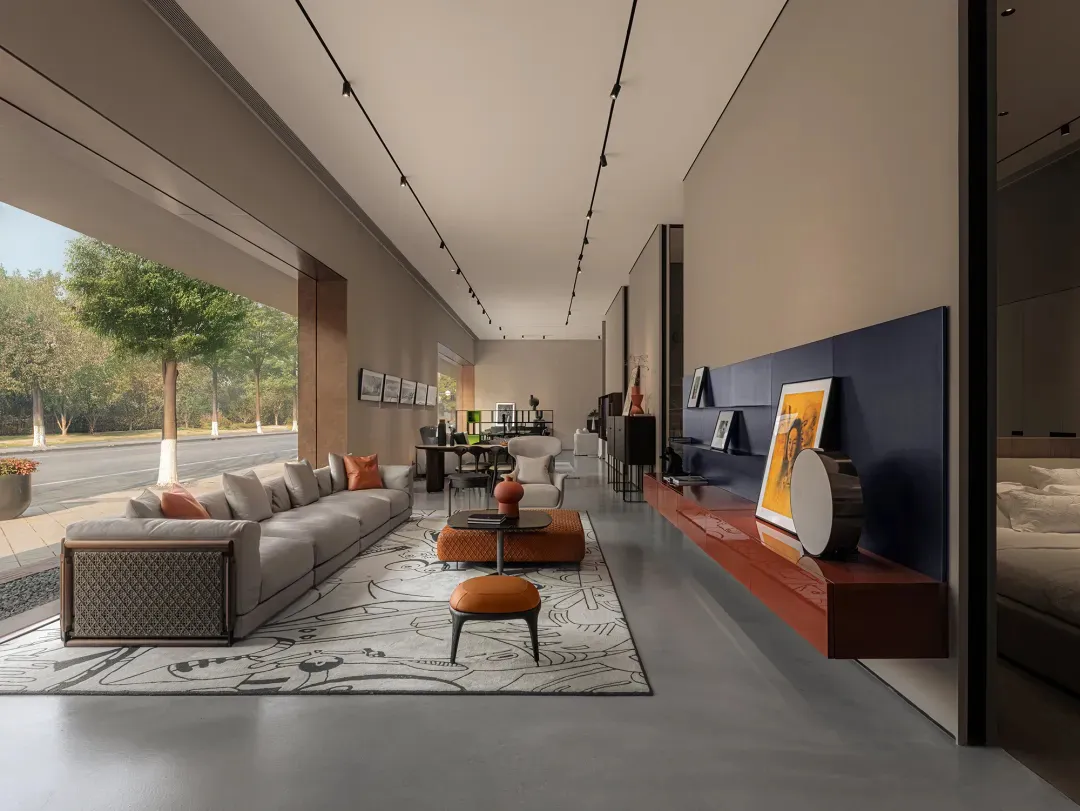 A modern interior space featuring a concrete wall, minimalist furniture, and a large window with a view of greenery.