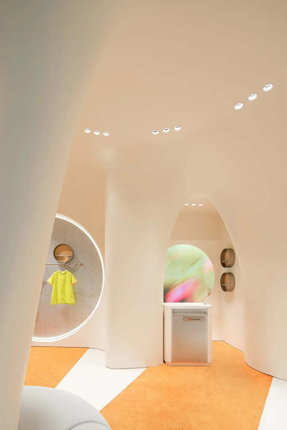Interior of a modern clothing shop featuring minimalist white concrete walls and floors.