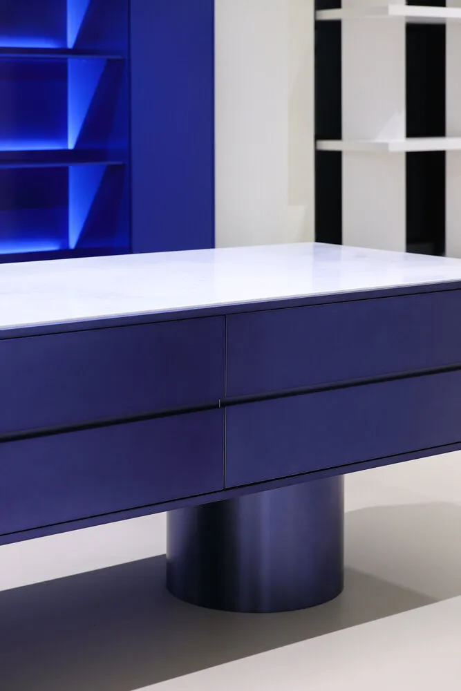 A minimalist furniture piece with a metal base and a marble top.