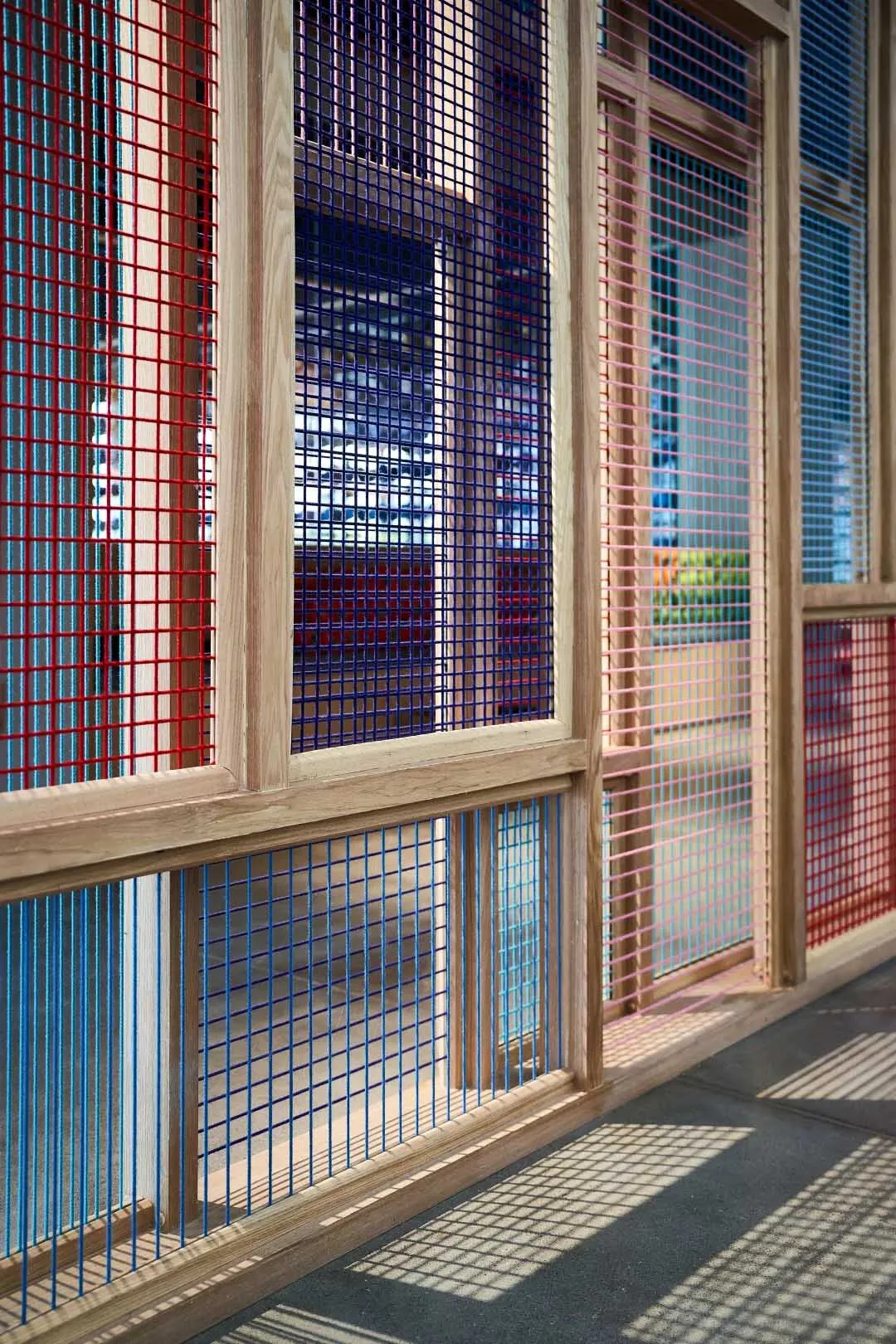 Modern interior featuring red, blue, and pink metal gratings on wooden frames