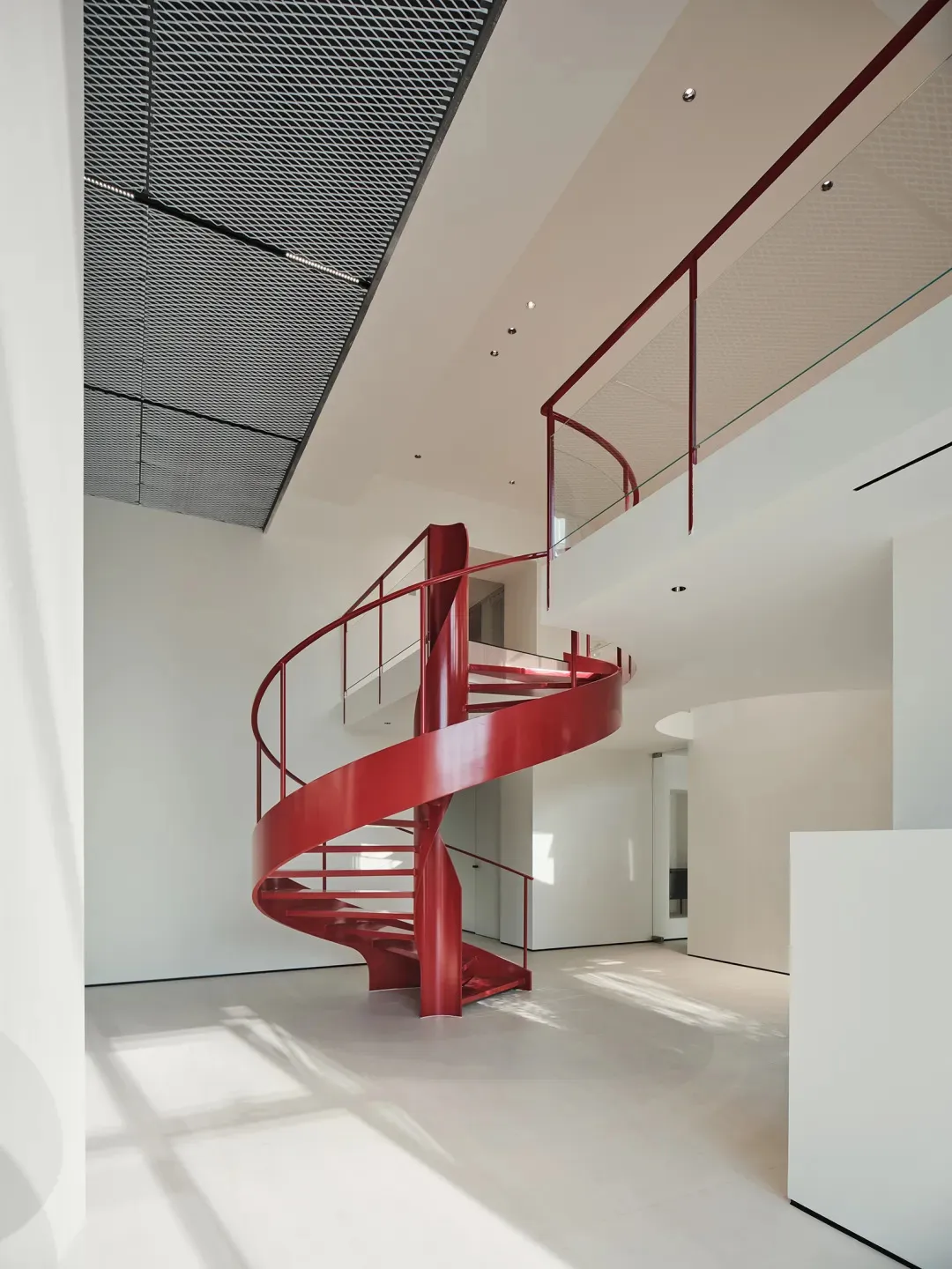 A modern interior design featuring a contemporary red metal spiral staircase.