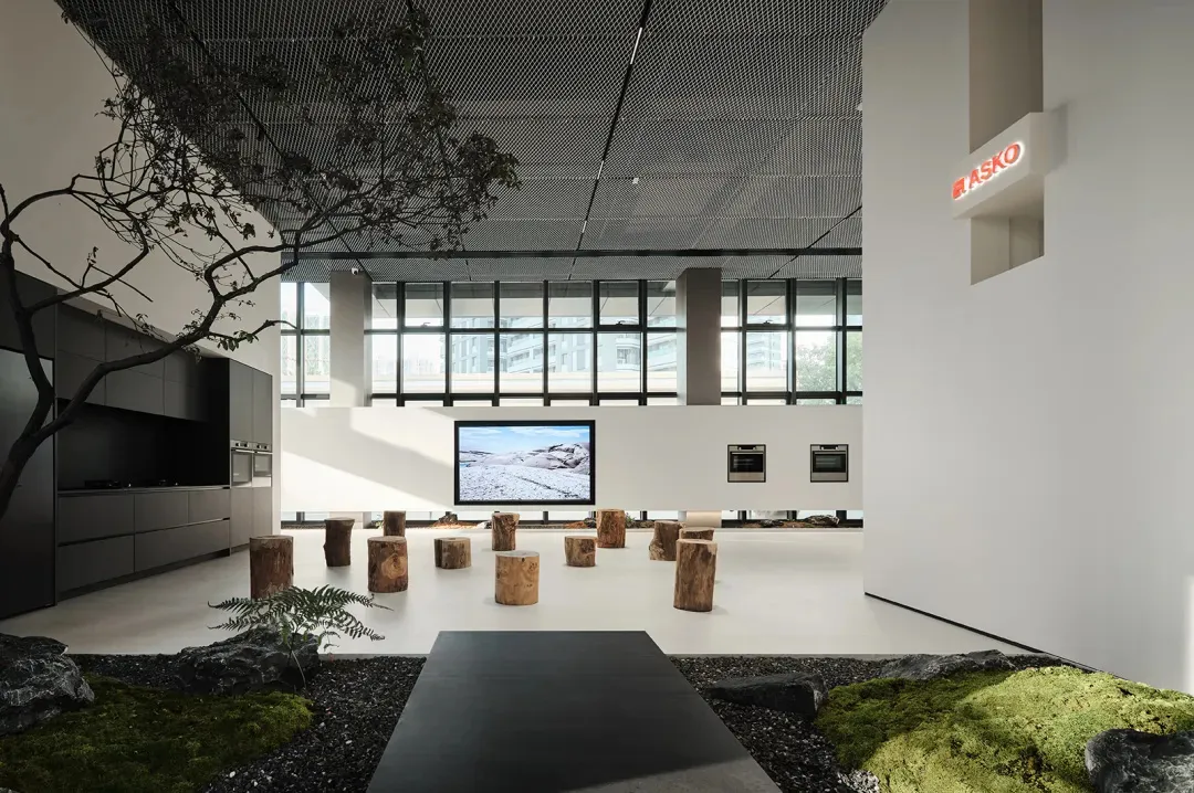 現代廚房展示空間,配有木質吧台椅與大型螢幕,螢幕上顯示雪景。