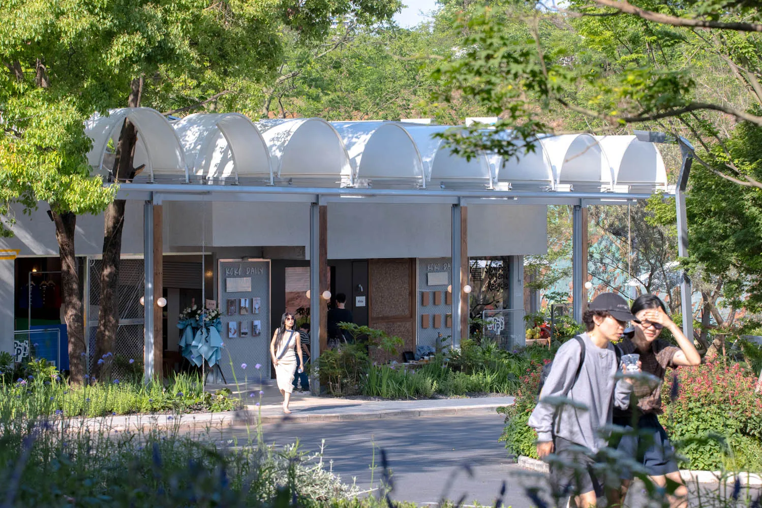 現代混凝土店面搭配白色遮陽篷，前景擺放鮮花。