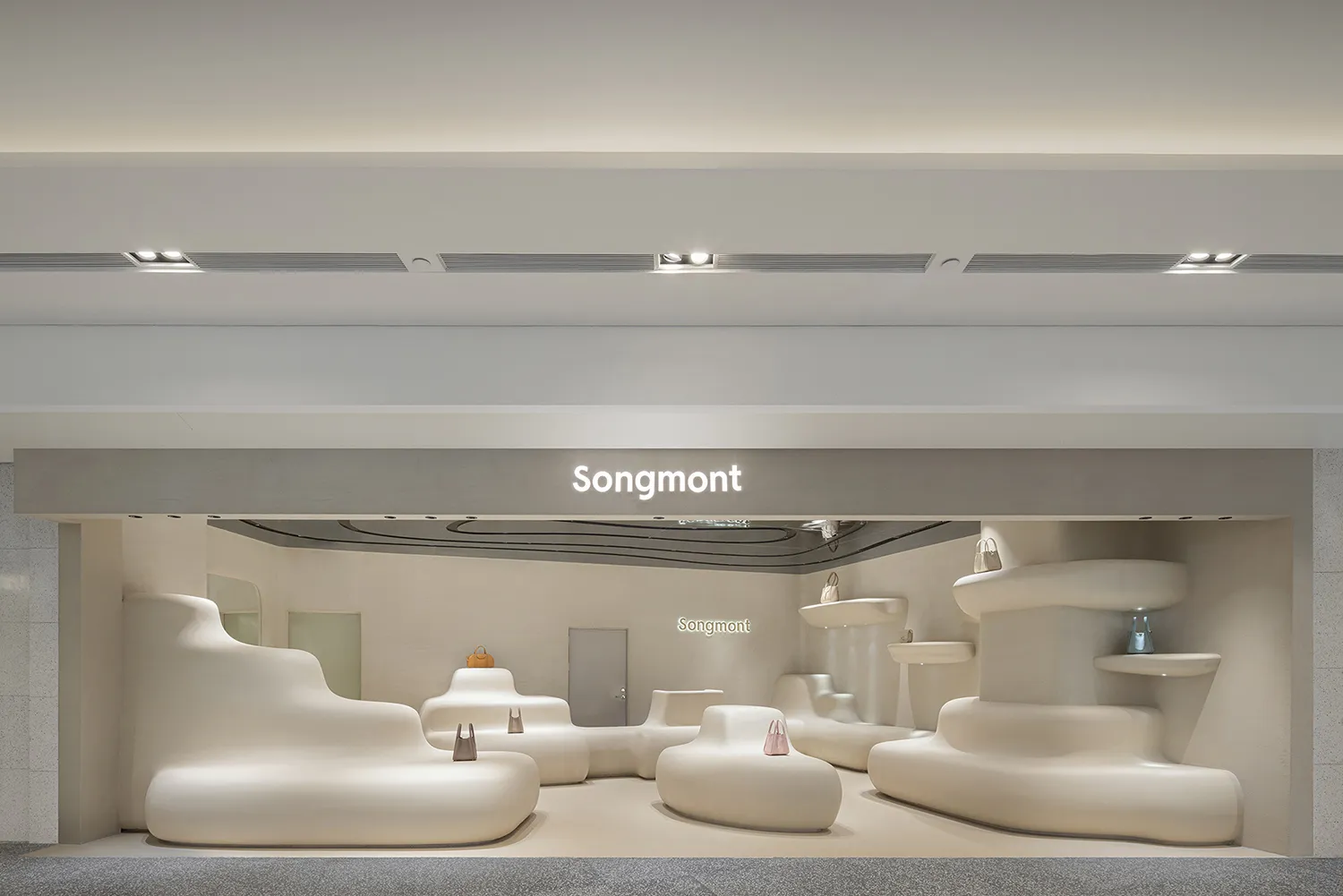 Modern minimalist retail storefront with white, curved furniture and signage for Songmont.