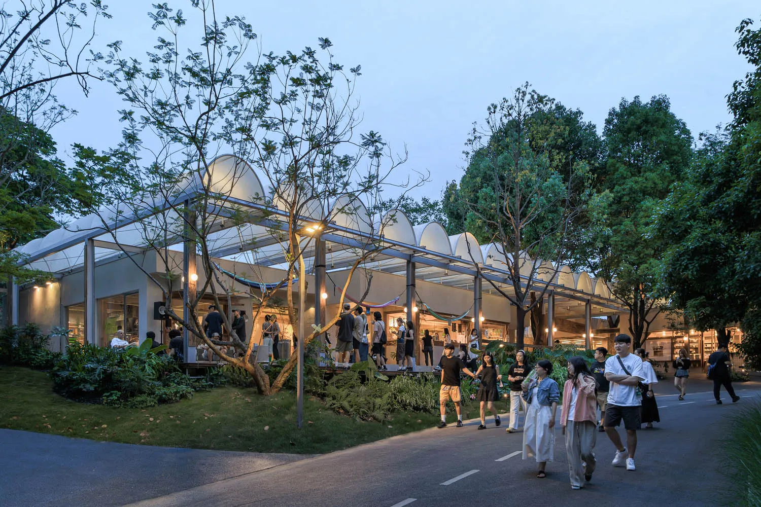 A modern public space featuring glass walls, metal structures, and fabric elements.