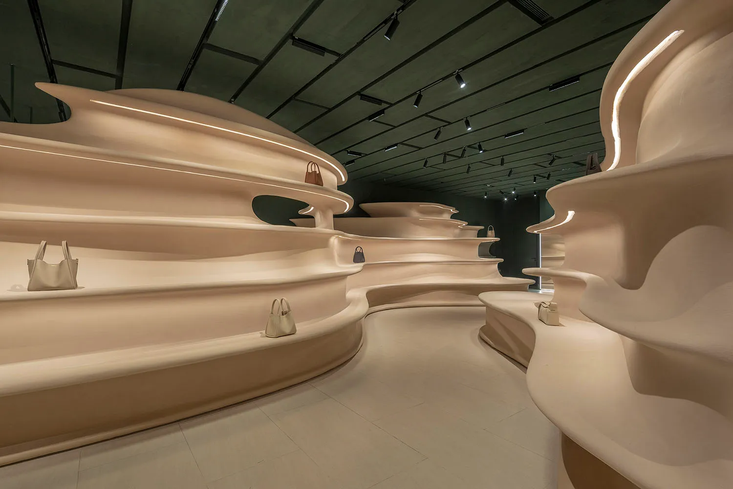 Modern retail interior featuring a sculptural plaster storefront display with handbags.